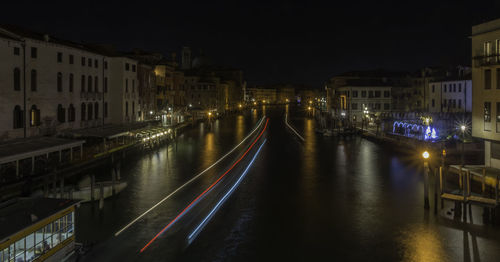 Illuminated canal amidst buildings in city at night