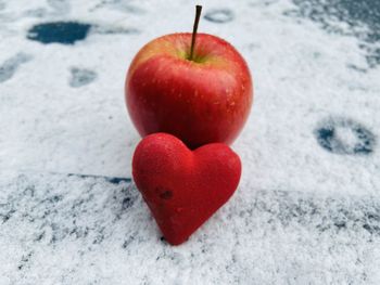 Red apple with red heart on snow