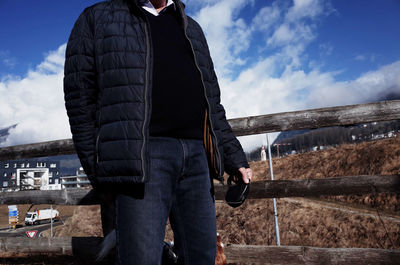 Man standing on cart against sky