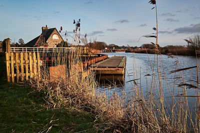 Abandoned house by lake against sky