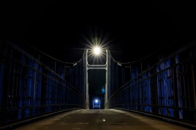 Empty road along footbridge at night