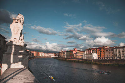 Statue of bridge over river against cloudy sky