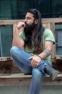 Young man looking away while sitting on seat