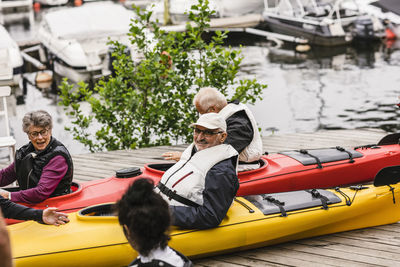 Senior men and women sitting in kayaks on jetty during kayaking course