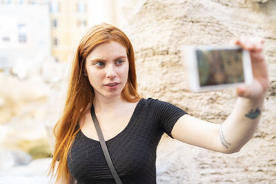 Young ginger woman taking selfie in city