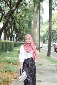 Young woman standing against trees