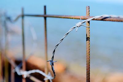 Close-up of barbed wire on fence against sky