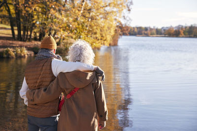 Rear view of woman standing by lake