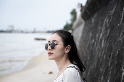 Portrait of young woman wearing sunglasses against sky