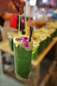 Cropped image of person holding drink in bamboo at khlong lat mayom floating market