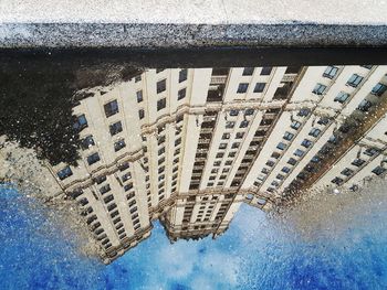 Reflection of building in puddle on street