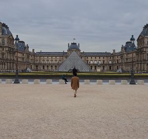 Rear view of people walking on historical building