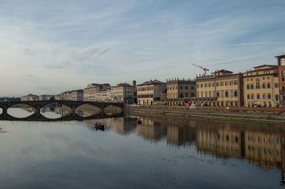 Bridge over river by buildings against sky