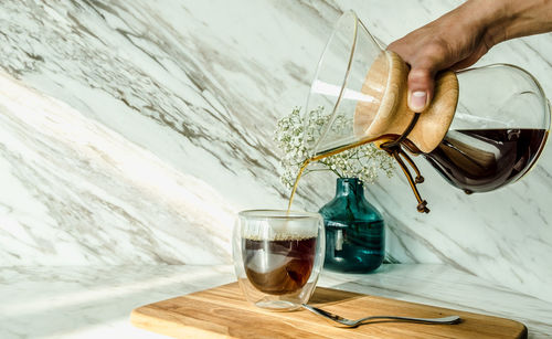 Midsection of person pouring wine in glass on table