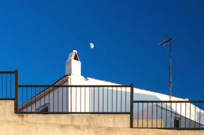 Low angle view of building against clear blue sky with the moon 