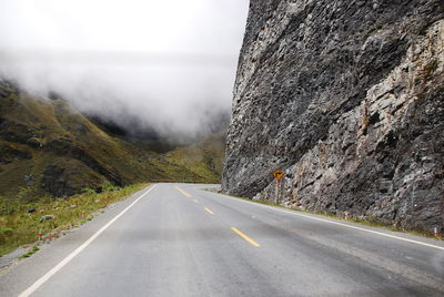 Road leading towards mountains against sky