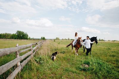 Couple riding horse on field