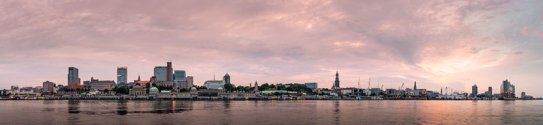 Panoramic view of river and buildings against sky during sunset