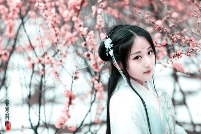 Portrait of young woman against cherry tree