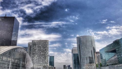 Low angle view of modern buildings against cloudy sky