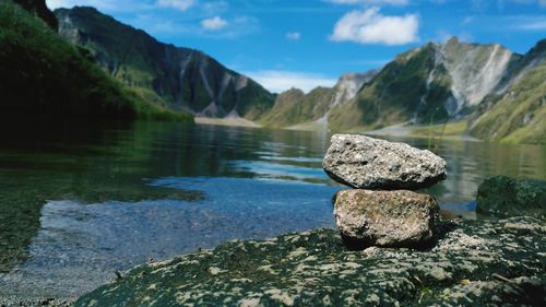 Close-up of rocks in lake against mountains