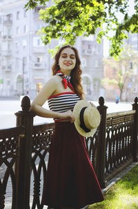 Portrait of smiling young woman sitting on railing