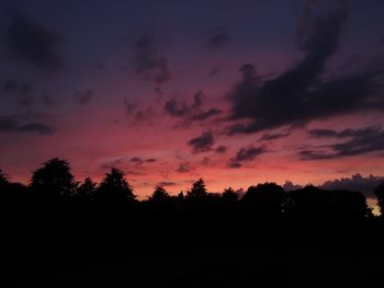 Silhouette trees against dramatic sky during sunset