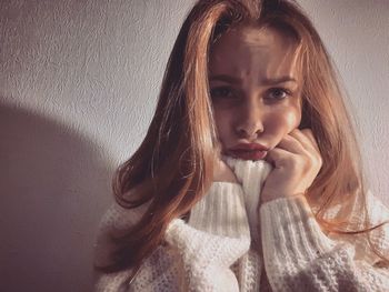 Portrait of beautiful young woman against wall