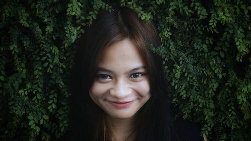 Portrait of smiling young woman by leaves