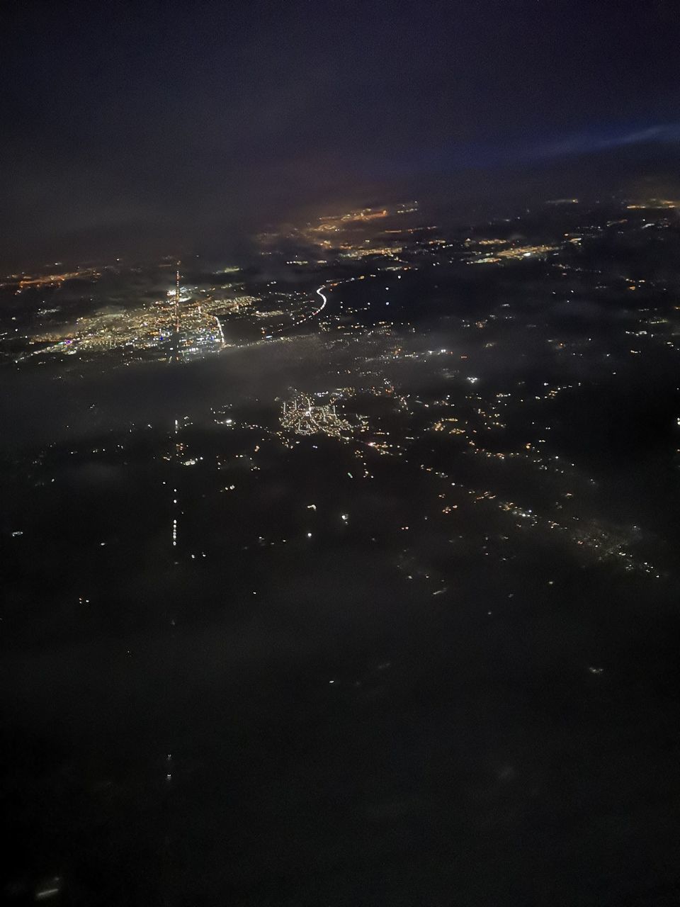 AERIAL VIEW OF ILLUMINATED CITY BUILDINGS AGAINST SKY AT NIGHT