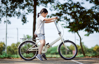Side view of woman with bicycle against trees