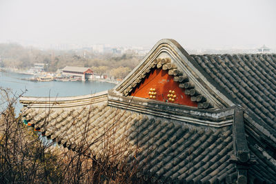 Tilt image of building by river against sky