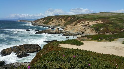 Curved rugged coastal view of sea against blue cloudy sky