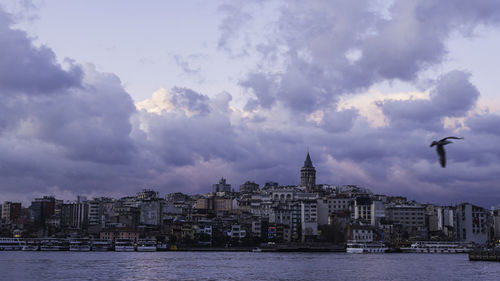 View of buildings at waterfront against cloudy sky
