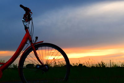 Bicycle on field against sky during sunset