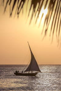 Silhouette sailboat in sea against sky during sunset