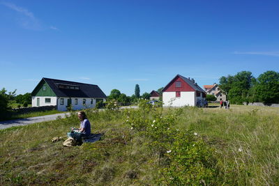 Boy on field by house against clear sky