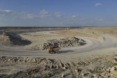 Dump truck moving on construction site against sky