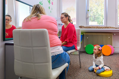 Mother and young daughter in therapist office during counselling assesmment meeting.