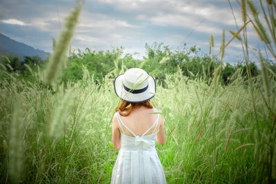 Woman wearing hat standing on field against sky