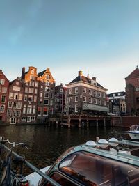 Canal by buildings in city against sky