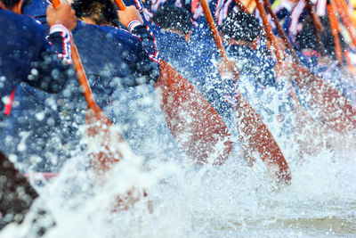 Rear view of men oaring during boat race