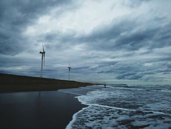 Traditional windmill by sea against sky