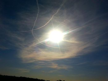 Low angle view of sun shining through clouds