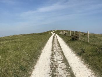 Road amidst field against sky