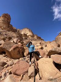 Full length of woman on rock against blue sky