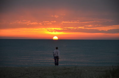 Wife looking at sea against sky during sunset