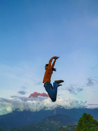 Low angle view of man jumping against sky