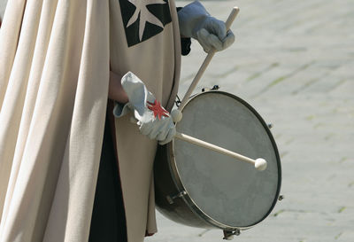 Midsection of person wearing costume playing dum on street