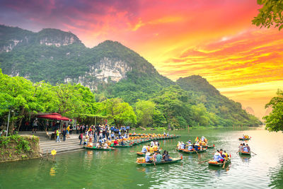 People on boats against sky during sunset